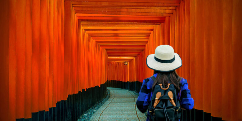 Woman traveler with backpack at fushimi inari taisha shrine in Kyoto, Japan.